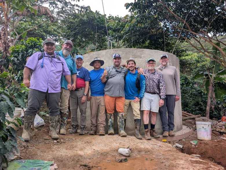 Nine volunteers and local compañeros lined up in front of the finished concrete storage tank
