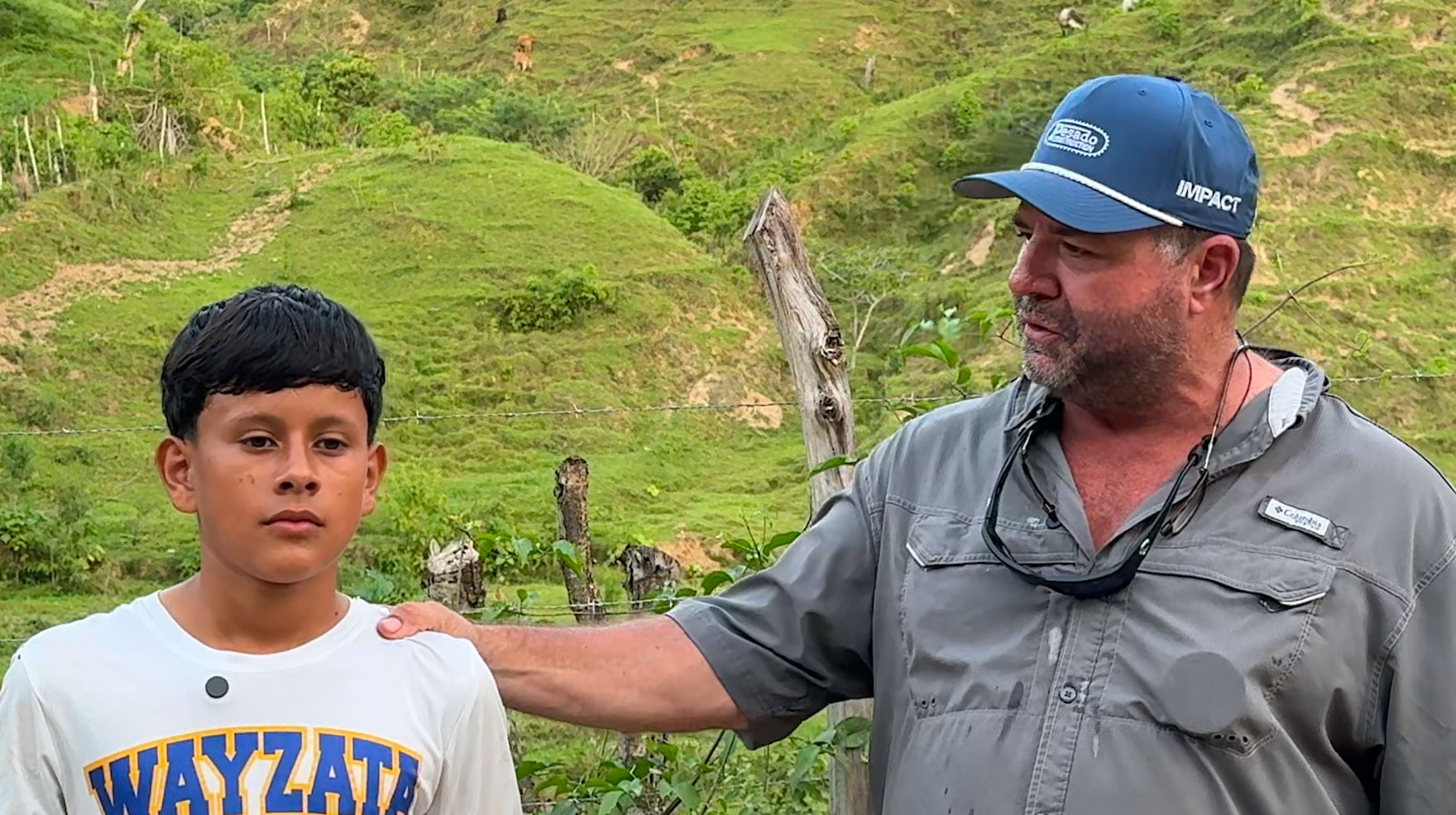 The community of El Guanito greets the team outside a whitewashed schoolhouse with a balloon arch and a hand-lettered Bienvenidos Impact sign